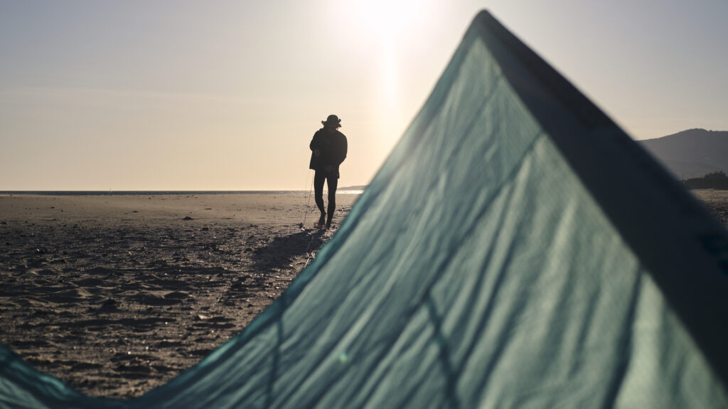 Kitesurf-Schüler baut F-One Bandit bei Sonnenuntergang am Strand in Tarifa auf – Rental bei High Spirits
