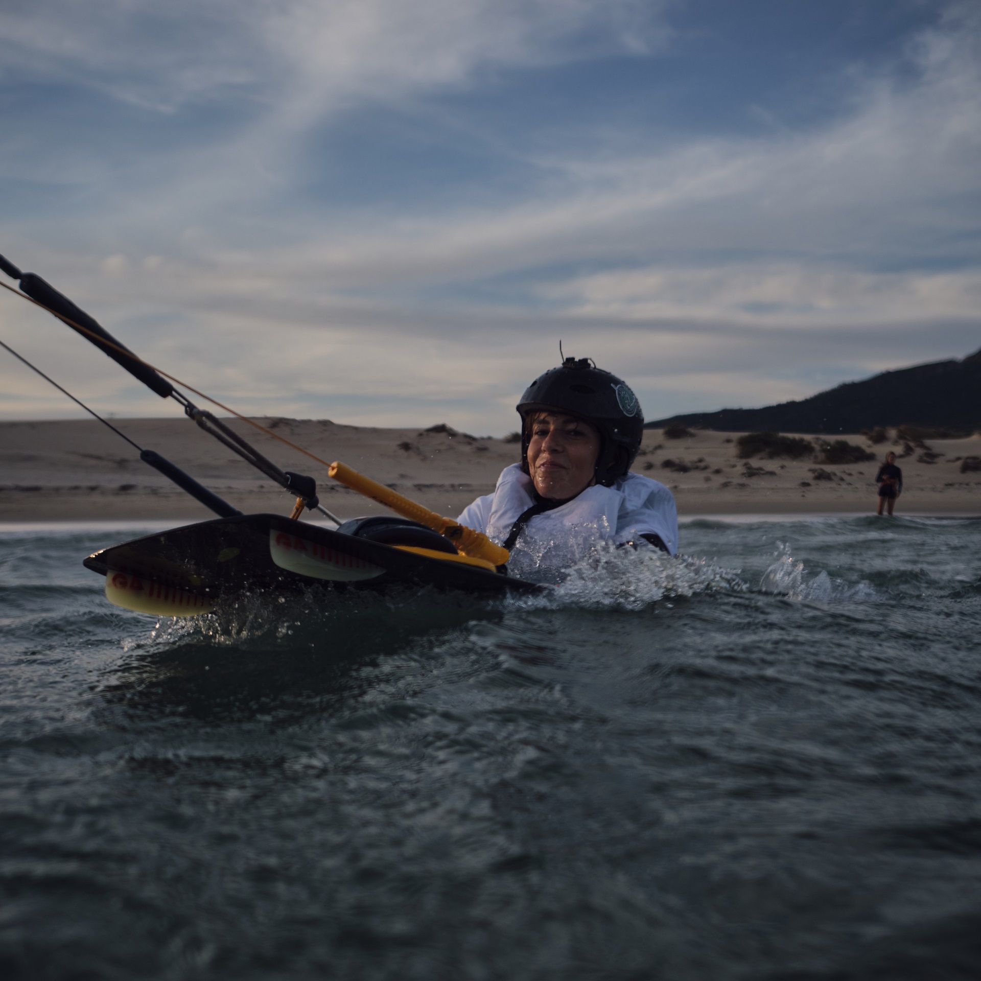 Kursantka ćwicząca body drag z deską podczas kursu kitesurfingu w Tarifie.