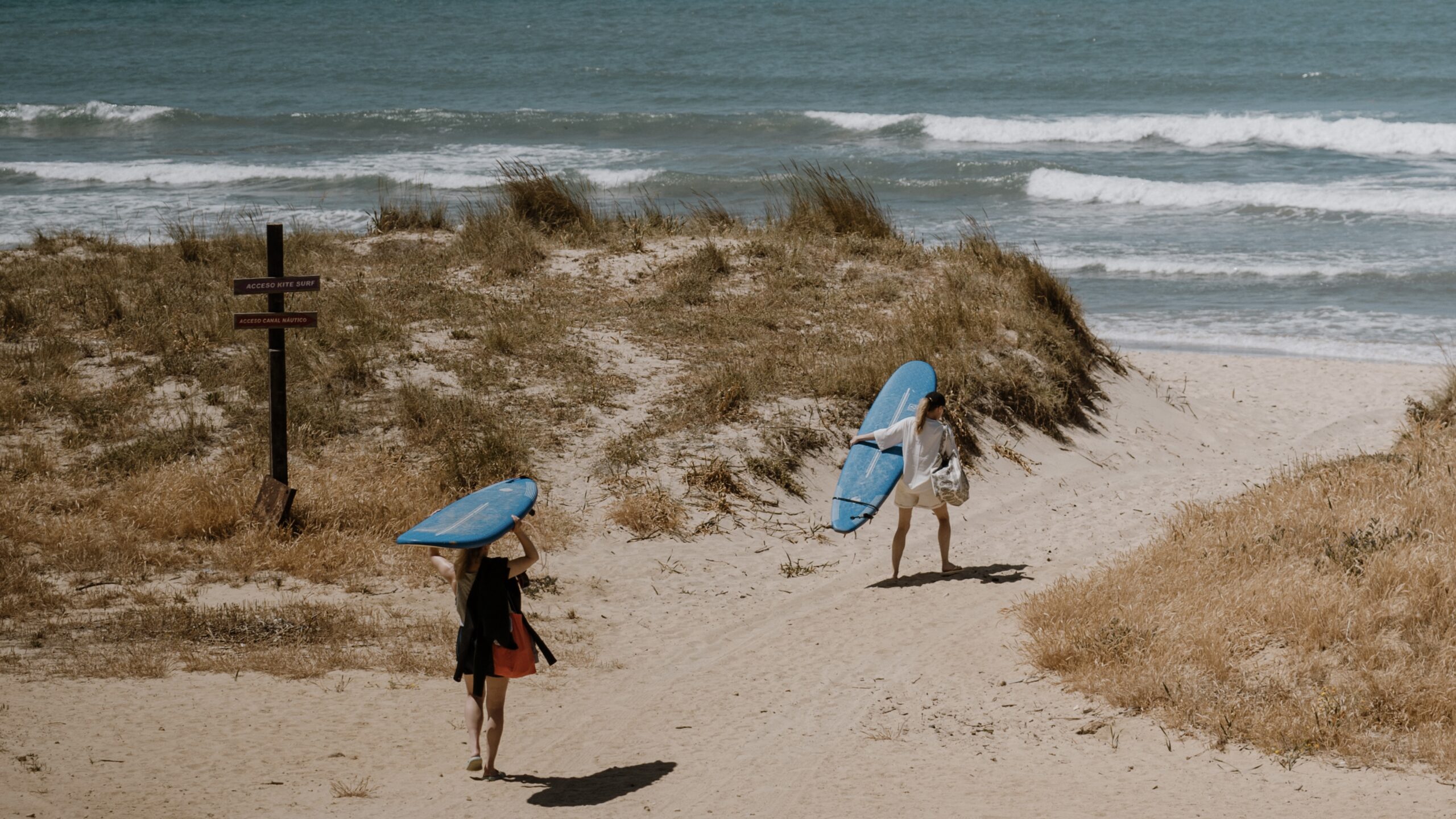 Grupo de alumnos caminando hacia la playa con sus tablas de surf antes de una clase de surf en Tarifa. 