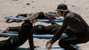 Surflehrer erklärt die ersten Trockenübungen während eines Surfkurses in Tarifa